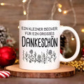 Eine hochwertige 11-Unzen-Keramik-Kaffeetasse mit stilvollem weißem Design, floralen Mustern und einem deutschen Dankesausdruck. Nur handwaschbar, geeignet für wiederholten Gebrauch und ein tolles Geschenk.